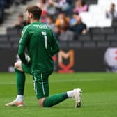 Andrew Fisher taking the knee earlier this season as part of the EFL’s anti-racism message. Dons will now stand arm-in-arm in the centre circle as part of their own anti-discrimination message, believing taking the knee is losing impact