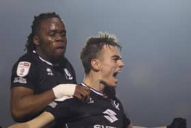Peter Kioso joins Scott Twine in celebration after Dons came from 2-0 down against Lincoln City to win it 3-2 in the final minute