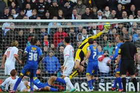 Jon Otsemobor watches on as his ‘Heel of God’ flick lofts over Neil Sullivan back in December 2012 when MK Dons beat AFC Wimbledon in the first meeting between the sides