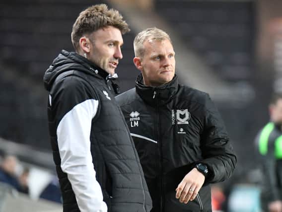 Chris Hogg and Liam Manning discuss tactics on the sidelines. The pair have both admitted to trying to keep MK Dons grounded amidst their excellent run of form since the turn of the year