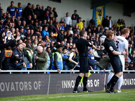 AFC Wimbledon supporters throw the ball at Dean Lewington and referee James Oldham during the 1-1 draw with MK Dons at the Cherry Red Records Stadium