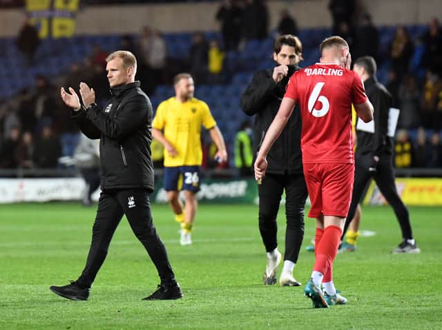 <p>Liam Manning applauds the travelling 1,600 MK Dons supporters after the defeat to Oxford United</p>