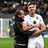 Warren O’Hora shares a laugh with coach David Wright. The defender said Dons are feeling no more pressure to win on Saturday against Plymouth than they normally do, despite an automatic promotion spot being the potential prize.