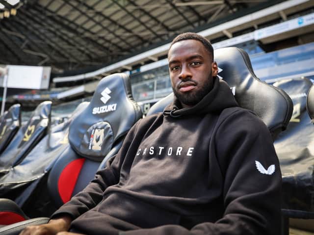 <p>Dons striker Mo Eisa sporting a Castore hoodie. The brand will take over from Errea as the new kit manufacturer from next season</p>