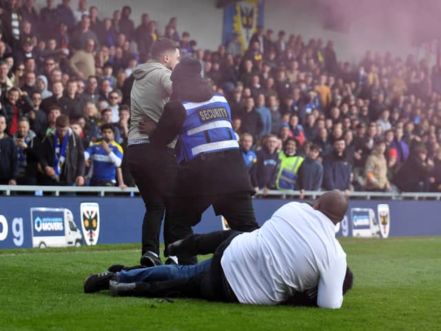 Stewards tackle someone invading the pitch during last season’s heated match between MK Dons and AFC Wimbledon at Plough Lane last season