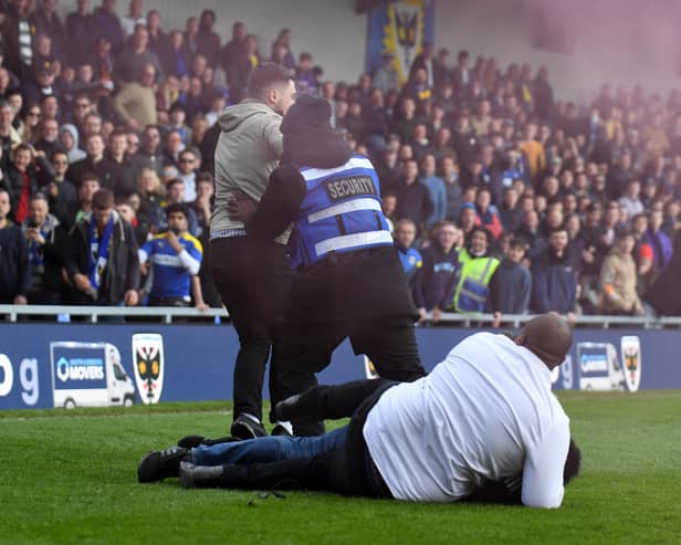 Stewards tackle someone invading the pitch during last season’s heated match between MK Dons and AFC Wimbledon at Plough Lane last season