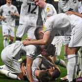MK Dons pile on to celebrate Bradley Johnson’s winning goal against Port Vale on Tuesday night to secure their first league win of the season, lifting them off the bottom of the table