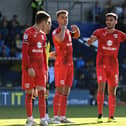 Warren O’Hora and Jack Tucker bark orders at Conor Grant during the 2-1 win over Oxford United on Saturday. Dons’ last eight goals conceded have come from dead ball situations