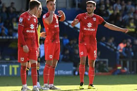 Warren O’Hora and Jack Tucker bark orders at Conor Grant during the 2-1 win over Oxford United on Saturday. Dons’ last eight goals conceded have come from dead ball situations