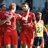 Will Grigg, Dean Lewington and Warren O’Hora celebrate MK Dons’ win over Oxford United last time out