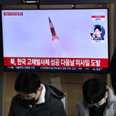 A man watches a television screen showing a news broadcast with file footage of a North Korean missile test, at a railway station in Seoul on December 31, 2022