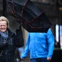 A woman battles to keep control of her umbrella as she walks through a rain shower in Glasgow.