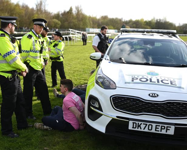 An animal rights protester is apprehended by police officers ahead of the Grand National. 