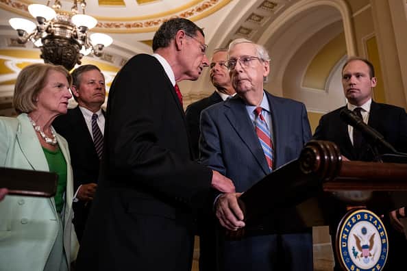 WASHINGTON, DC - JULY 26: (L-R) Sen. John Barrasso (R-WY) reaches out to help Senate Minority Leader Mitch McConnell (R-KY) after McConnell froze and stopped talking at the microphones during a news conference after a lunch meeting with Senate Republicans U.S. Capitol 26, 2023 in Washington, DC. Also pictured, L-R, Sen. Shelley Moore Capito (R-WV), Sen. Steve Daines (R-MT), and Sen. John Thune (R-SD). McConnell was escorted back to his office and later returned to the news conference and answered questions. (Photo by Drew Angerer/Getty Images)