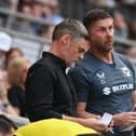 Graham Alexander and Chris Lucketti look over their notes in the dugout at Stadium MK