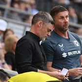 Graham Alexander and Chris Lucketti look over their notes in the dugout at Stadium MK