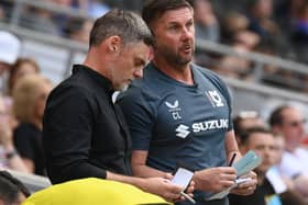 Graham Alexander and Chris Lucketti look over their notes in the dugout at Stadium MK