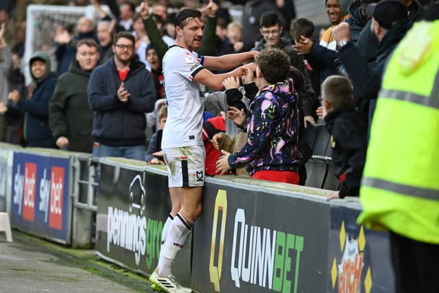 Captain Alex Gilbey celebrated with some young fans in the front row after his cross was put into his own net by Swindon’s George McEachran