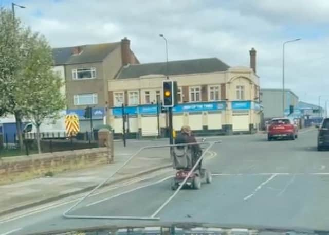 A man tows a metal fence from his mobility scooter in Grimsby. The man was spotted dragging the fence along as he stopped at traffic lights.