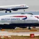 A British Airways plane lands as two other grounded planes sit on the runway at Heathrow Airport.