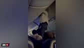 Passengers help man from overhead bin after 'strong turbulence'.