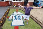 Bryn Nicholls stands next to the Jude Bellingham England shirt mural he has created in his front garden.