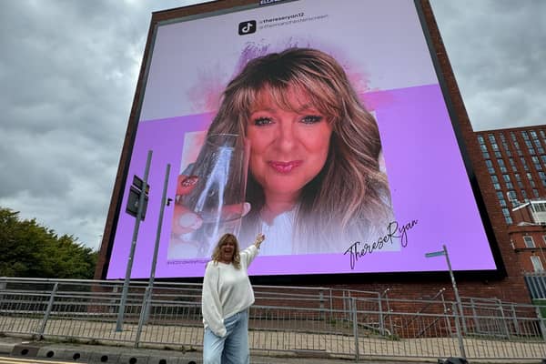 Theresa, 56, beside an image of herself on the OVC billboard in Manchester, paid for by her son Oliver Ryan. 