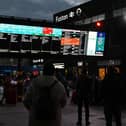 Rail travellers look at an electronic information board displaying train time information outside Euston Station in London. Photo: JUSTIN TALLIS/AFP via Getty Images