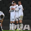 Tom Carroll and Alex Gilbey celebrate with goal-scorer Joe Tomlinson
