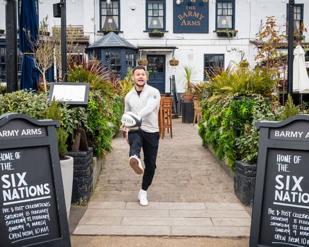 Former England rugby international Danny Care kicking a ball "into space" from outside the Greene King sport pub The Barmy Arms in Twickenham