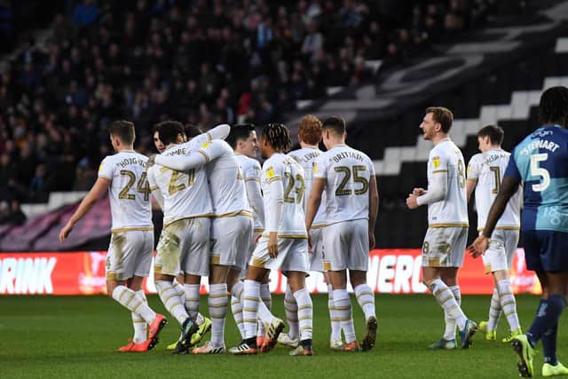 The players mob Gladwin after he scored Dons' second.