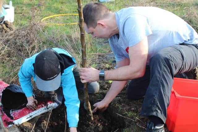 Mr Nelson and a student planting one of the trees
