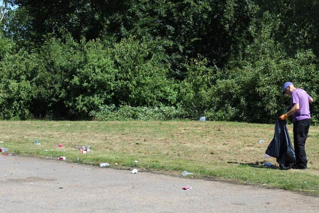 A ranger picks up litter left on parkland