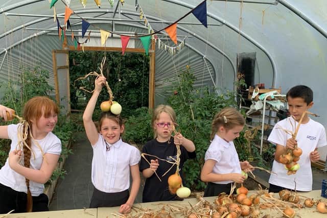 Children from St Mary and St Giles School  display their bumper crop of onions
