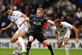 Spurs' Oliver Skipp is challenged by MK Dons pair Matt O'Riley and Scott Twine