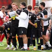 Liam Manning (far right) issues instructions to his players during a drinks break at Cheltenham Town