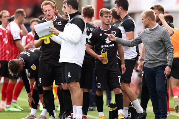 Liam Manning (far right) issues instructions to his players during a drinks break at Cheltenham Town