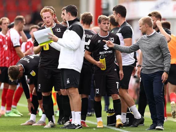 Liam Manning (far right) issues instructions to his players during a drinks break at Cheltenham Town