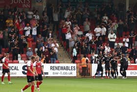 MK Dons' players and fans celebrate Hiram Boateng's late equaliser at Cheltenham Town on Saturday