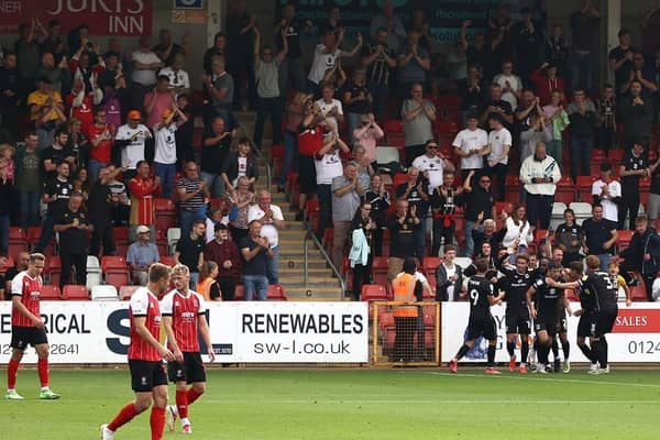 MK Dons' players and fans celebrate Hiram Boateng's late equaliser at Cheltenham Town on Saturday