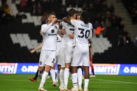 Scott Twine is mobbed by his MK Dons team-mates after scoring his first goal