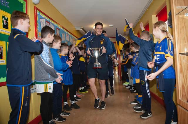 Coach Dermot McBride leads the Steelstown Brian Og's to the assembly hall at Hollybush Primary School last week. (Photo: Jim McCafferty)