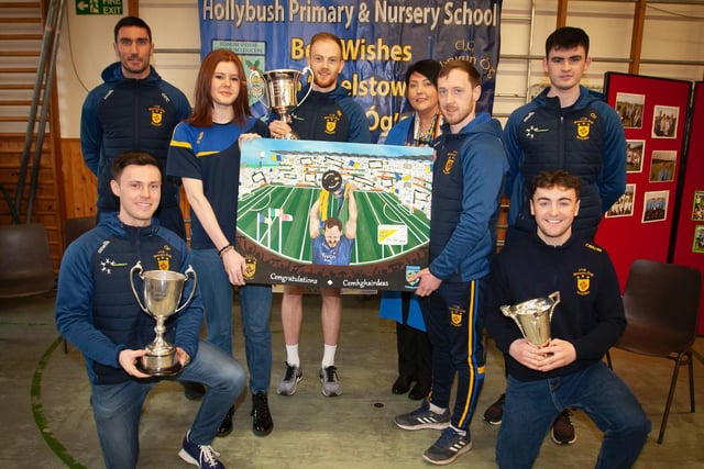 Former Hollybush PS pupil Saoirse O'Donnell hands over a painting recording the Steelstown victory at Croke Park to club captain, Neil Forester. Included is Ms. Teresa Duggan, Principal, and some of the Steelstown players.