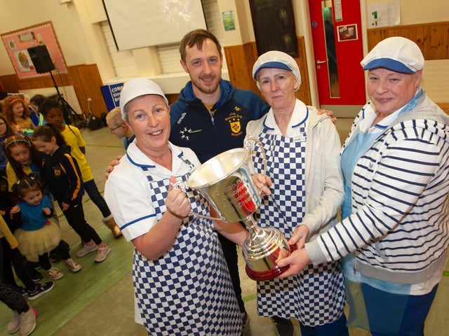 Steelstown captain Neil Forrester showing off the Kieran O'Sullivan Cup to some of the canteen staff at Hollybush Primary School.