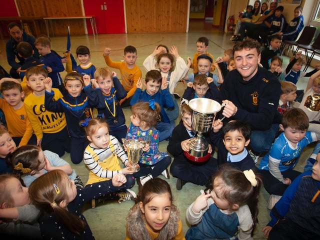 Steelstown Brian Ogs' player and former pupil, Cahir McMonagle, shows off the Kieran O'Sullivan Cup to some of the pupils during last week's visit to Hollybush Primary School.
