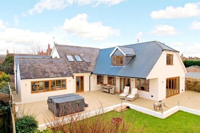 The attractive property features a composite decked area with lighting and hot tub overlooking an enclosed rear garden