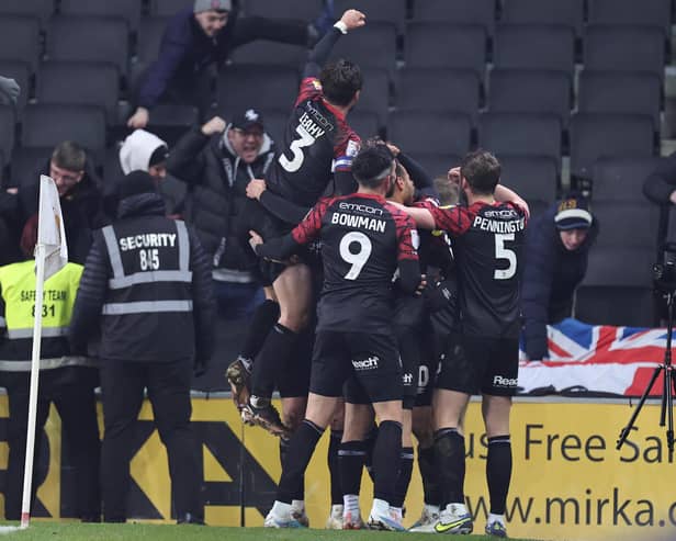 Shrewsbury Town players celebrate with their fans after Tom Bayliss had scored his side's winning goal over MK Dons