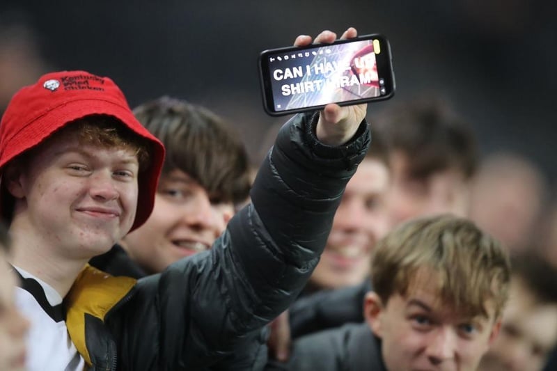 A young Milton Keynes Dons fan uses his mobile phone to ask Hiram Boateng for his shirt during the Sky Bet League One match between Milton Keynes Dons and Cheltenham Town at Stadium MK on March 08, 2022.