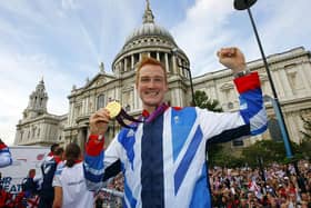 British Olympic gold medal winning athlete Greg Rutherford holds his long jump gold medal as he takes part in the parade passing St Paul's Cathedral during the London 2012 Victory Parade for Team GB.