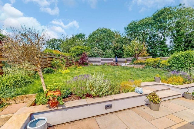 The rear garden includes a feature fence surround and patio area and tree, flower and shrub borders.